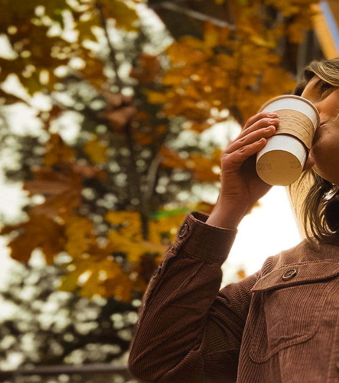 Women sipping a hot beverage with autumn leaves in the background
