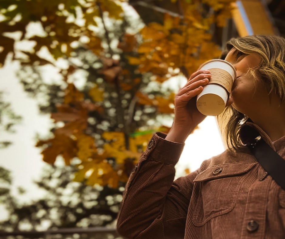 Women sipping a hot beverage with autumn leaves in the background