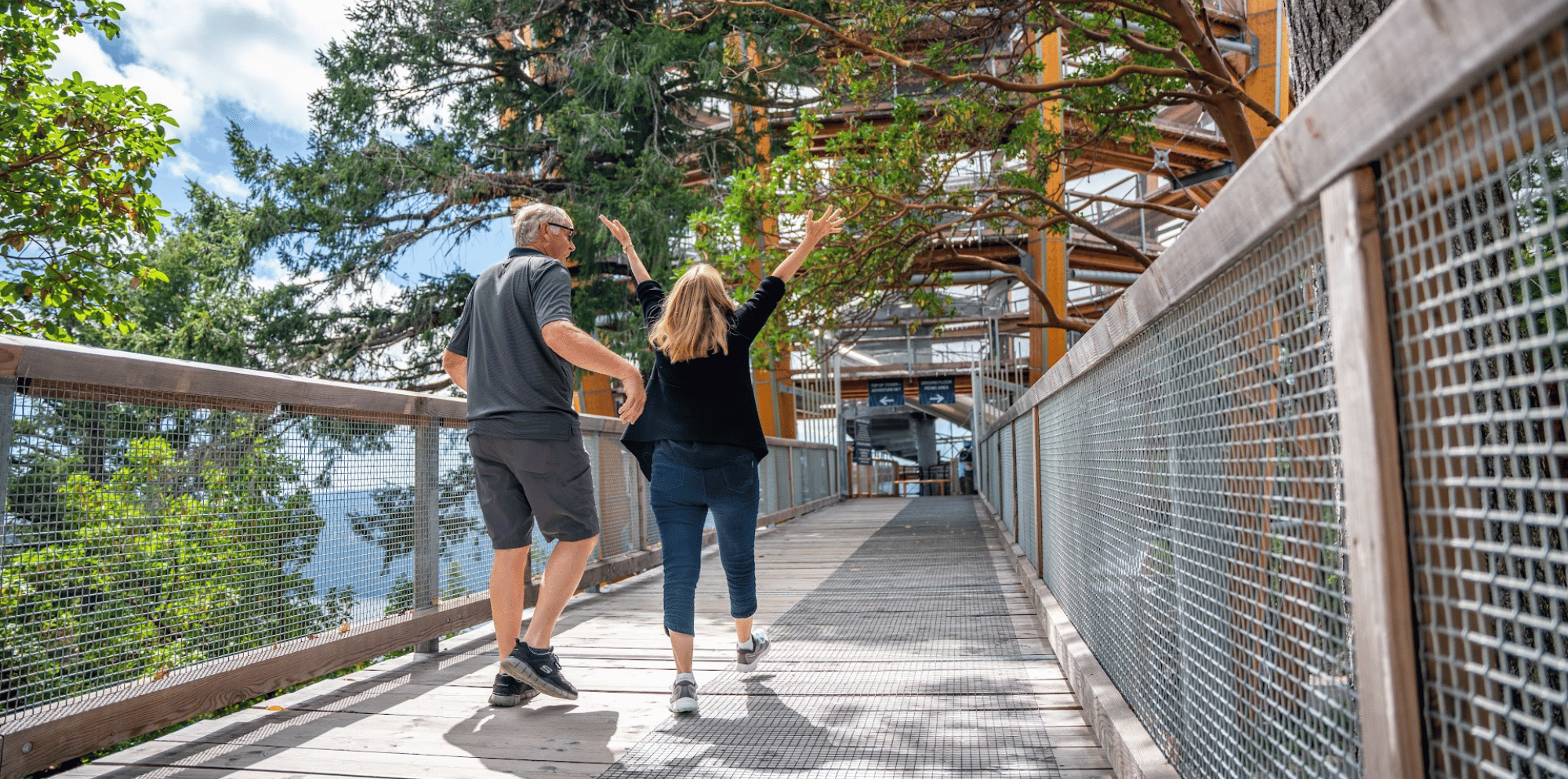 a man and a woman walking excitedly along the TreeWalk. You can see the Spiral Tower in the background