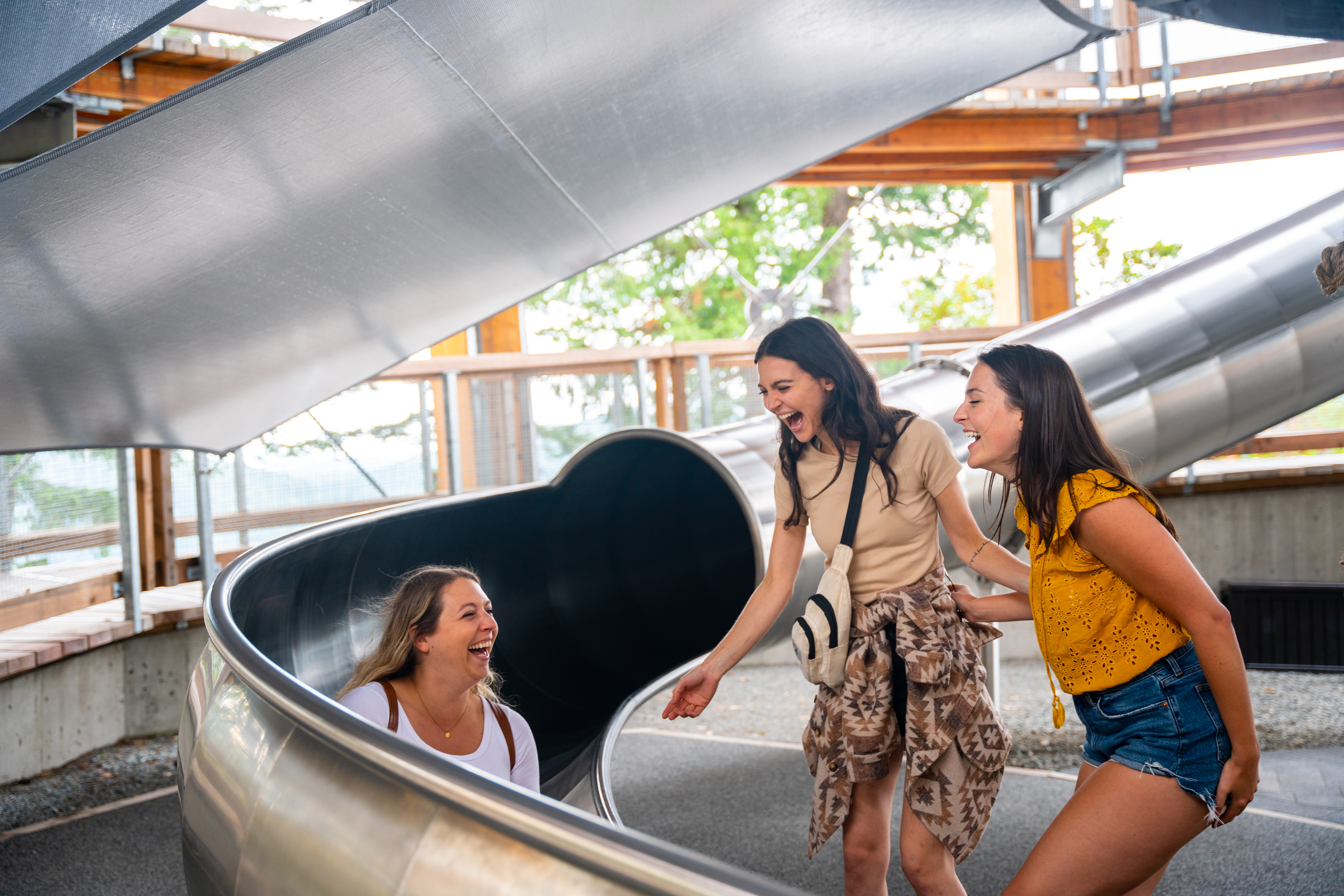 Three women laughing at the bottom of the Spiral Slide at Malahat SkyWalk